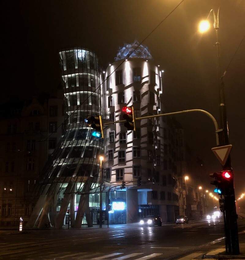 Ve tmě svítící Tančící dům na Řašínově nábřezí v Praze.